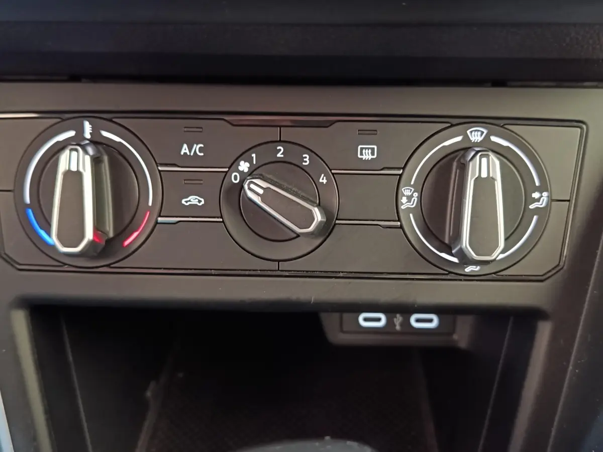 Vue rapprochée des commandes de climatisation manuelle et ports USB du Volkswagen Taigo gris foncé 2023.