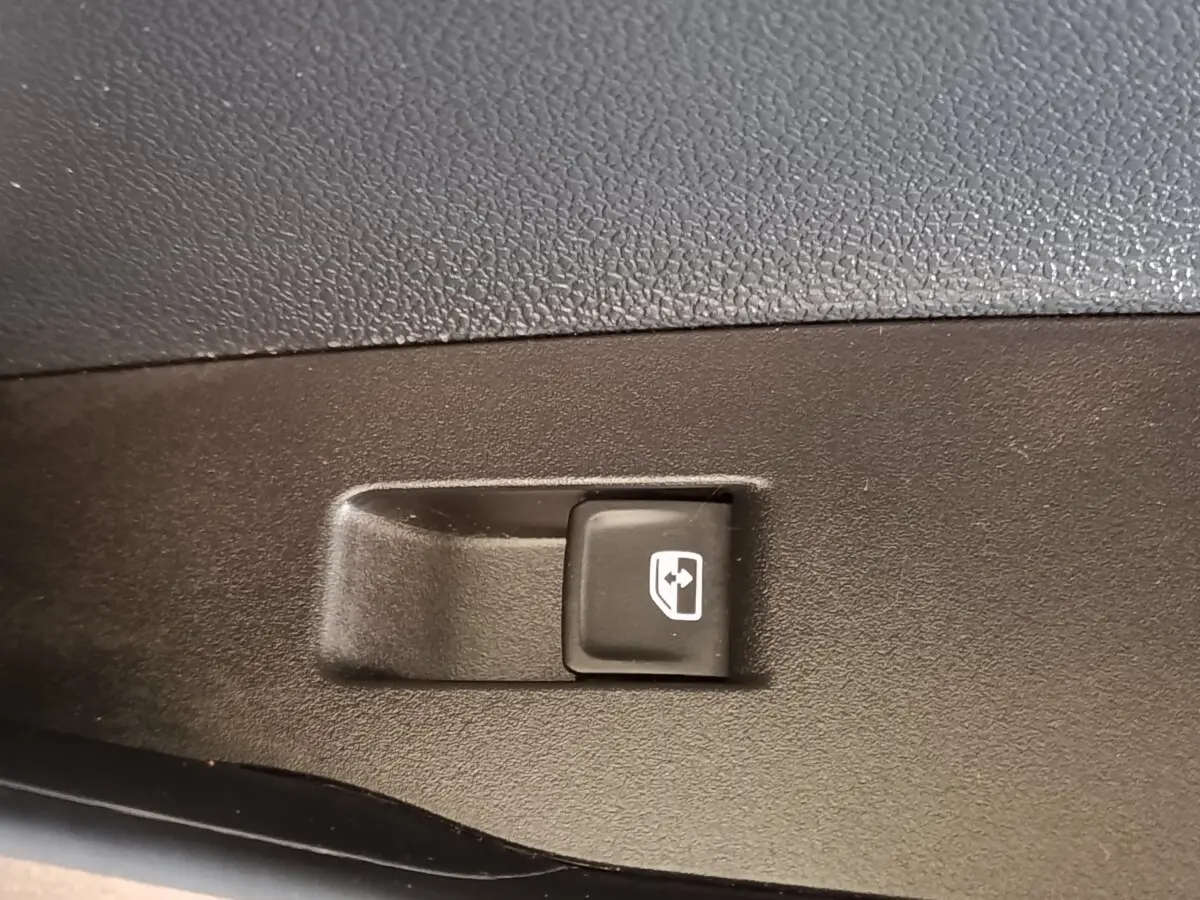 Bouton de commande de lève-vitre électrique sur panneau de porte intérieur noir du Volkswagen Taigo gris foncé.