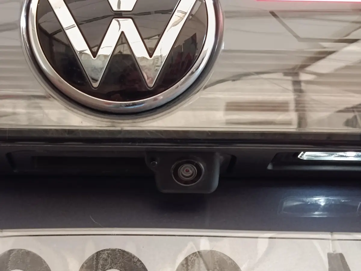 Gros plan sur la caméra de recul sous le logo Volkswagen d’un Taigo gris foncé 2023.
