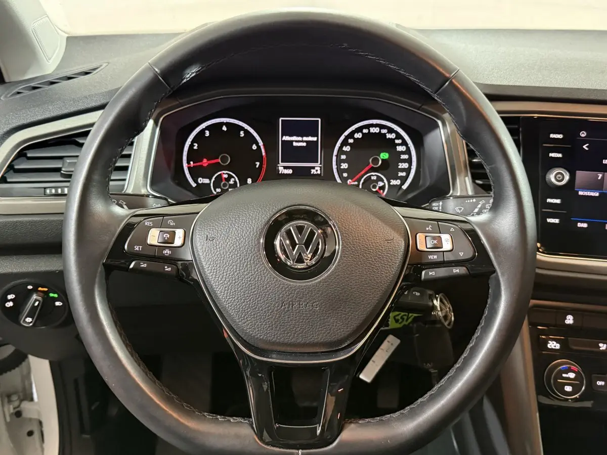 Vue rapprochée du volant cuir noir du Volkswagen T-Roc 2020 avec tableau de bord et écran tactile visibles.