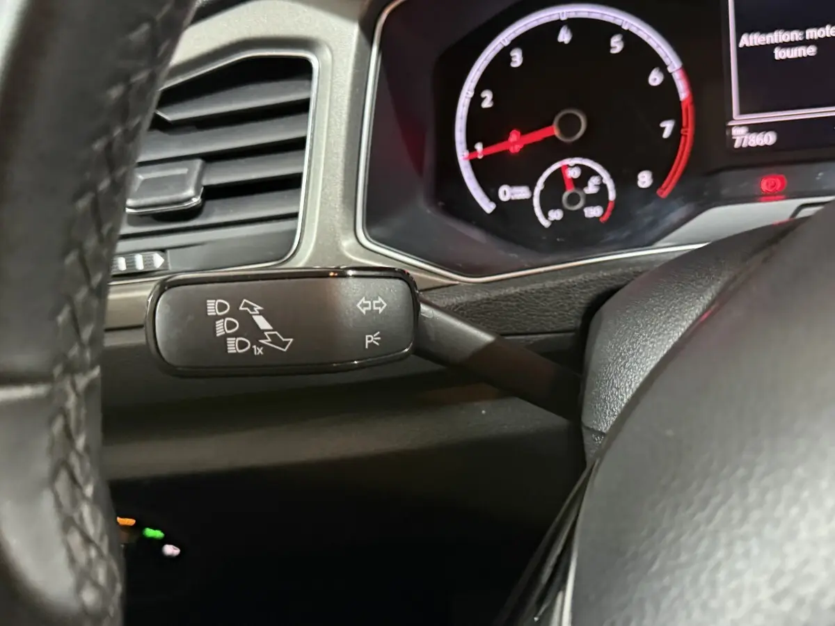 Gros plan sur le commodo gauche et le tableau de bord numérique du Volkswagen T-Roc blanc 2020, intérieur noir.