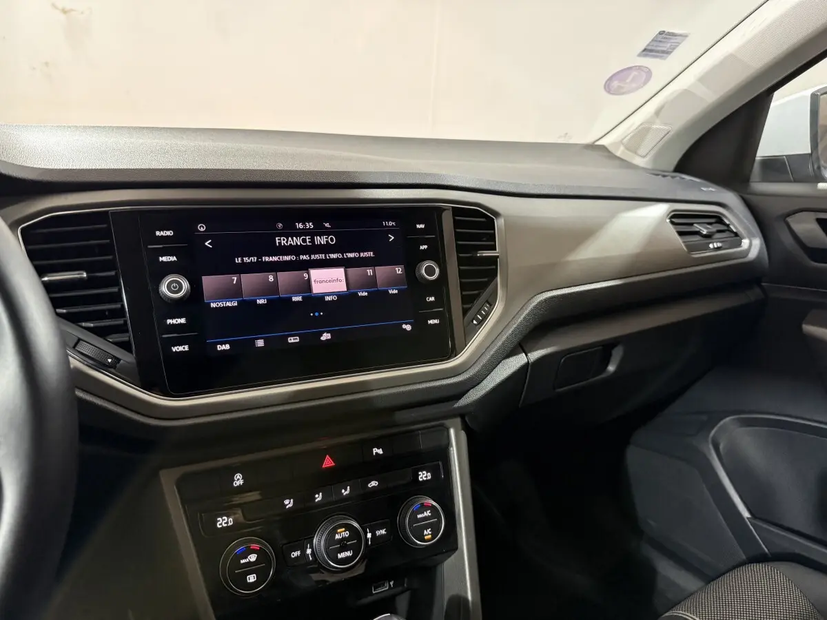 Intérieur du Volkswagen T-Roc blanc 2020, tableau de bord avec écran tactile 8 pouces et commandes climatisation visibles côté passager.