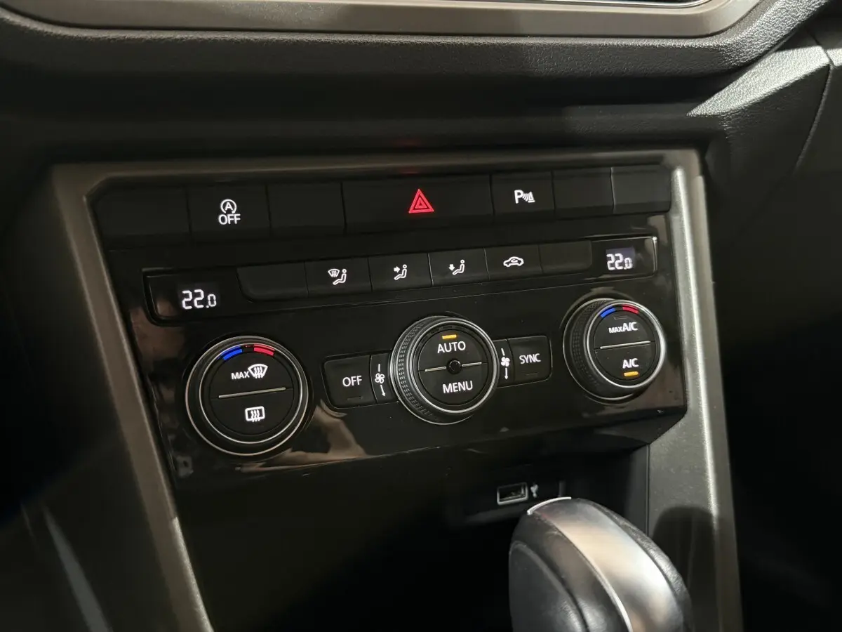 Panneau de commande de climatisation digitale du Volkswagen T-Roc 1.5 TSI blanc, avec réglages à 22°C visibles.