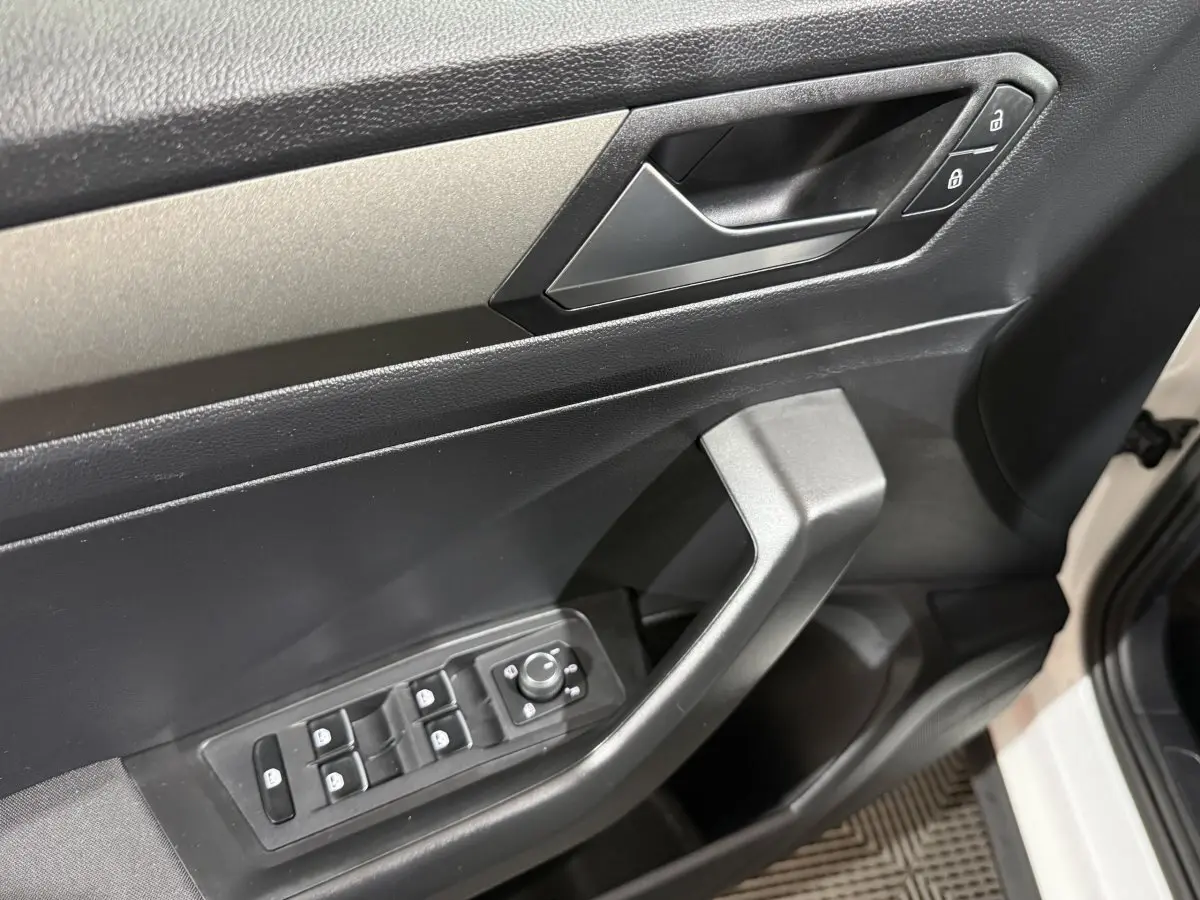 Gros plan sur la porte avant gauche blanche du Volkswagen T-Roc, montrant les commandes électriques et la poignée intérieure noire.