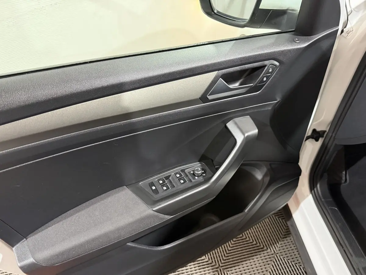 Vue intérieure de la porte côté conducteur du Volkswagen T-Roc blanc, avec commandes électriques des vitres et verrouillage.
