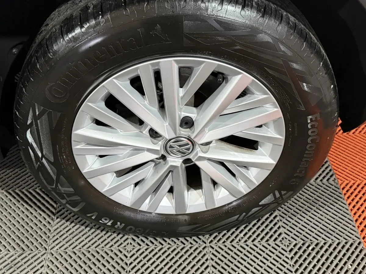Gros plan sur la jante argentée avec logo Volkswagen d'un Volkswagen T-Roc blanc, pneu Continental EcoContact 6 visible.