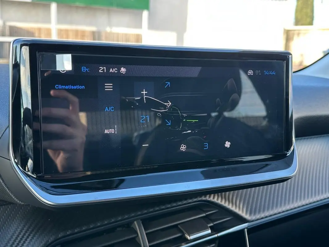 Écran tactile du tableau de bord de la Peugeot 208 Hybrid 110 blanc, affichant la climatisation à 21°C.