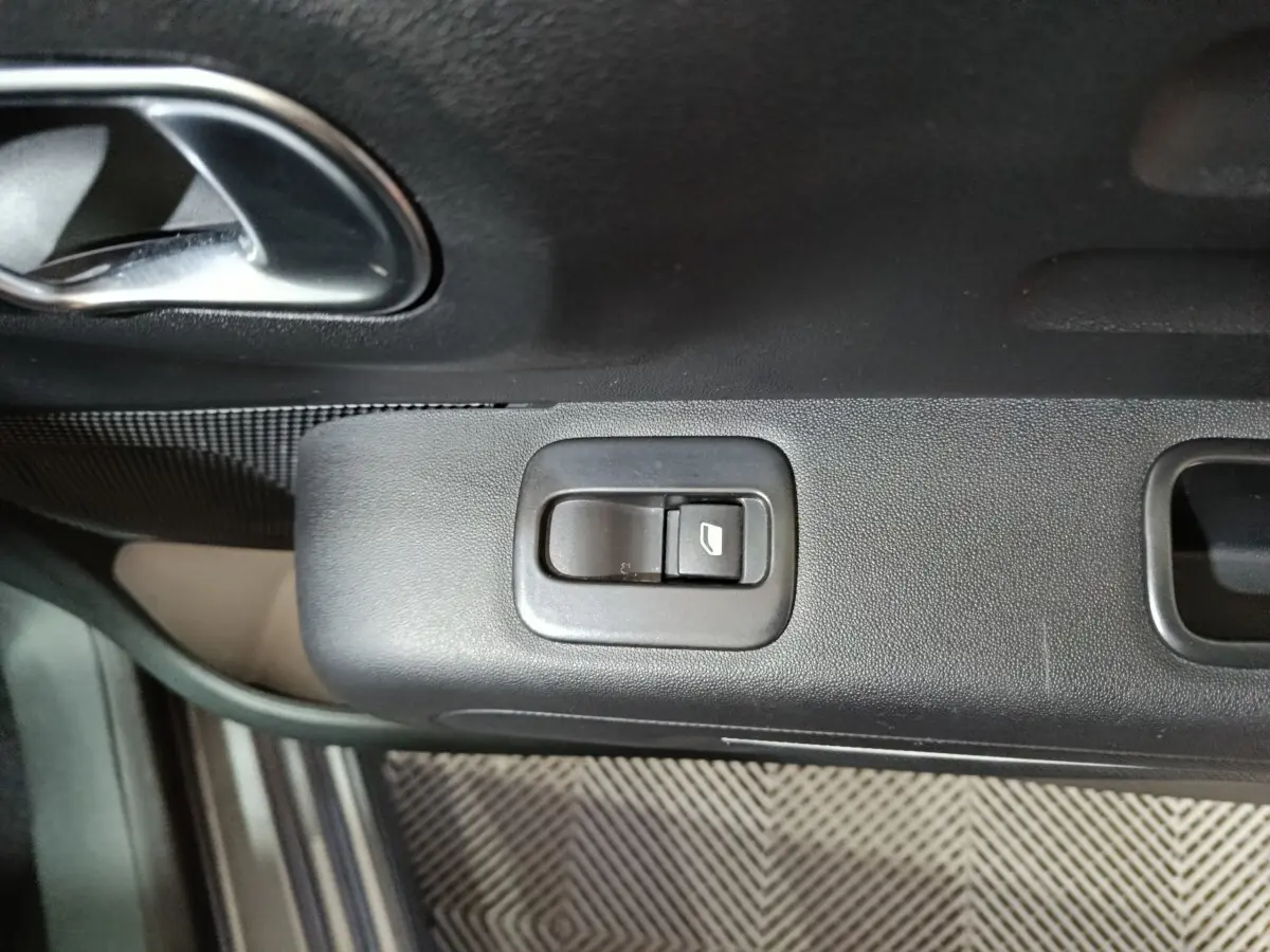 Gros plan sur la commande de lève-vitre côté conducteur d’une Citroën C3 gris foncé, intérieur noir.