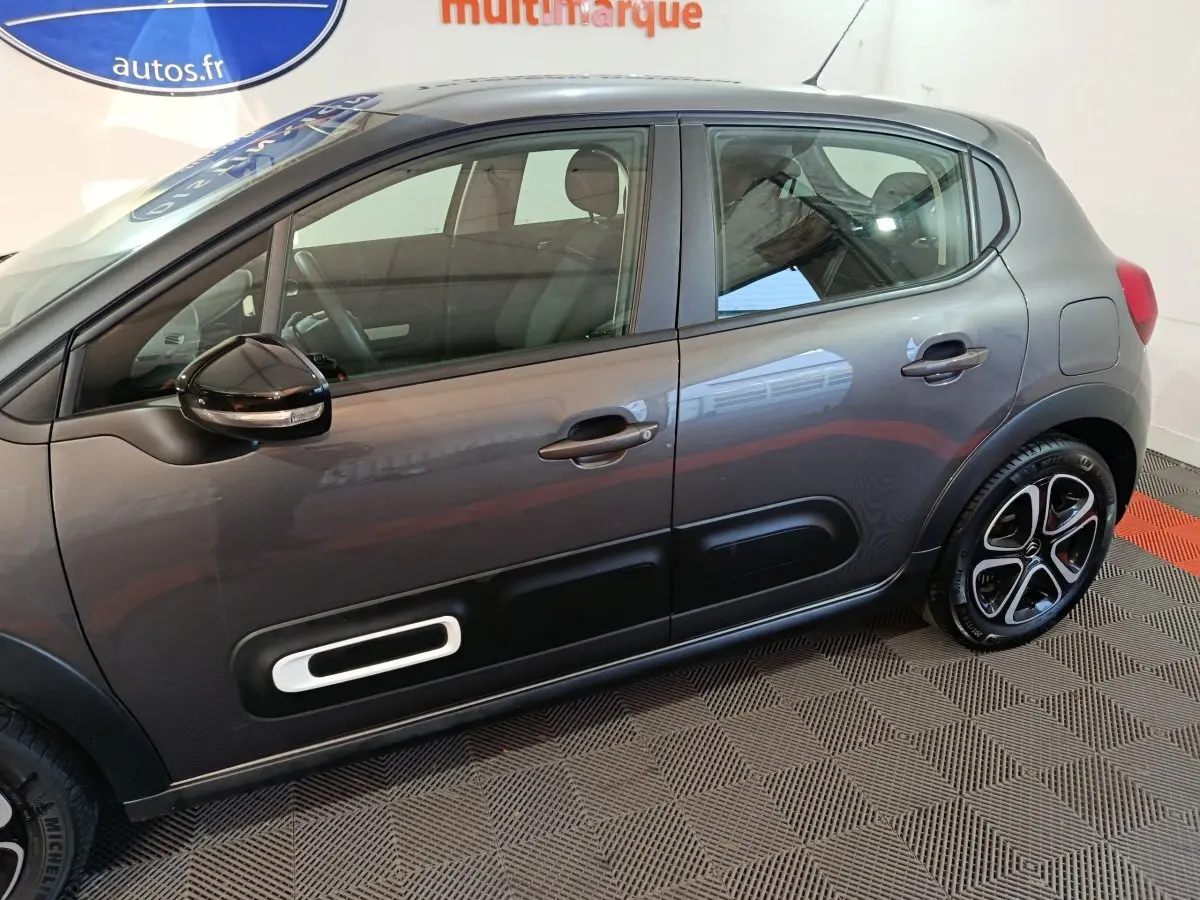 Vue de profil côté gauche d'une Citroën C3 gris foncé avec protections de porte noires et jantes stylisées.