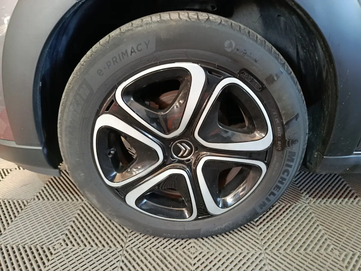 Gros plan sur la roue avant gauche d'une Citroën C3 gris foncé, avec jante alliage noire et argentée au design moderne.