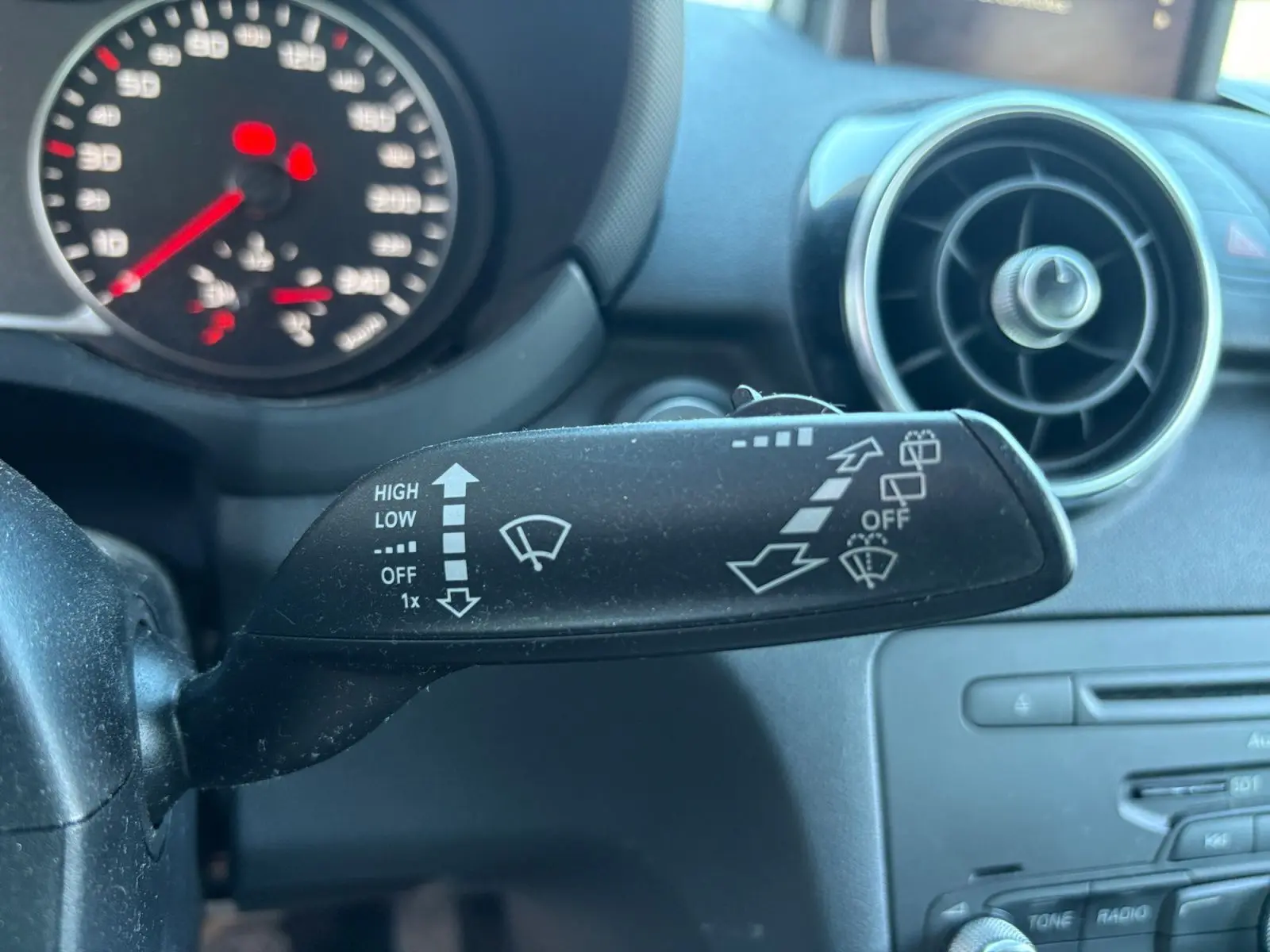 Gros plan sur la commande des essuie-glaces côté gauche du tableau de bord d'une Audi A1 Sportback grise avec toit noir.
