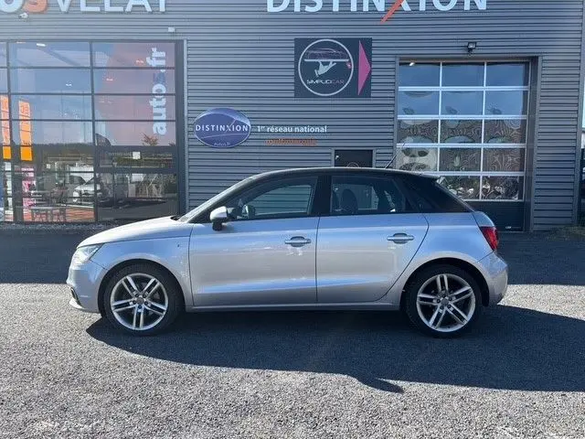 Vue de profil droit d'une Audi A1 Sportback grise avec toit noir, jantes alliage et finition S-Line visible.