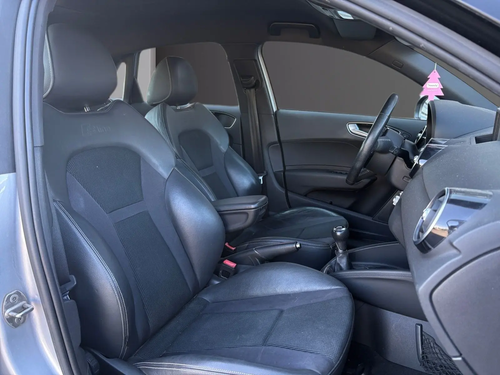Vue intérieure côté conducteur de l'Audi A1 Sportback 1.4 TFSI S-Line avec sièges sport noirs et accoudoir central.