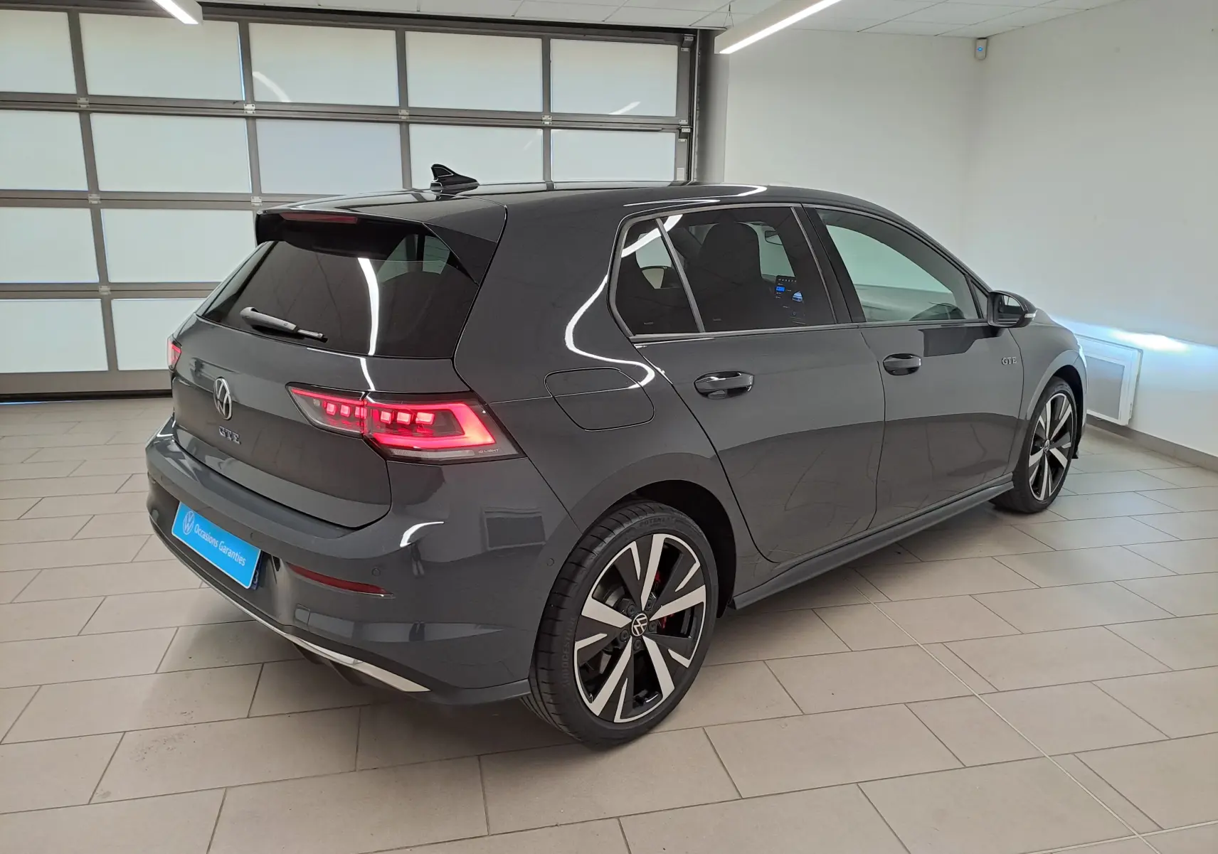 Volkswagen Golf 1.5 eHybrid 2025 gris Urano vue 3/4 arrière droit avec feux LED et jantes distinctives GTE.