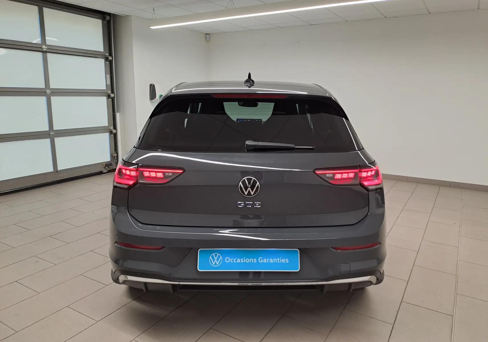 Vue arrière d'une Volkswagen Golf 1.5 eHybrid 272 DSG6 GTE 2025 en gris Urano avec feux LED allumés en intérieur.