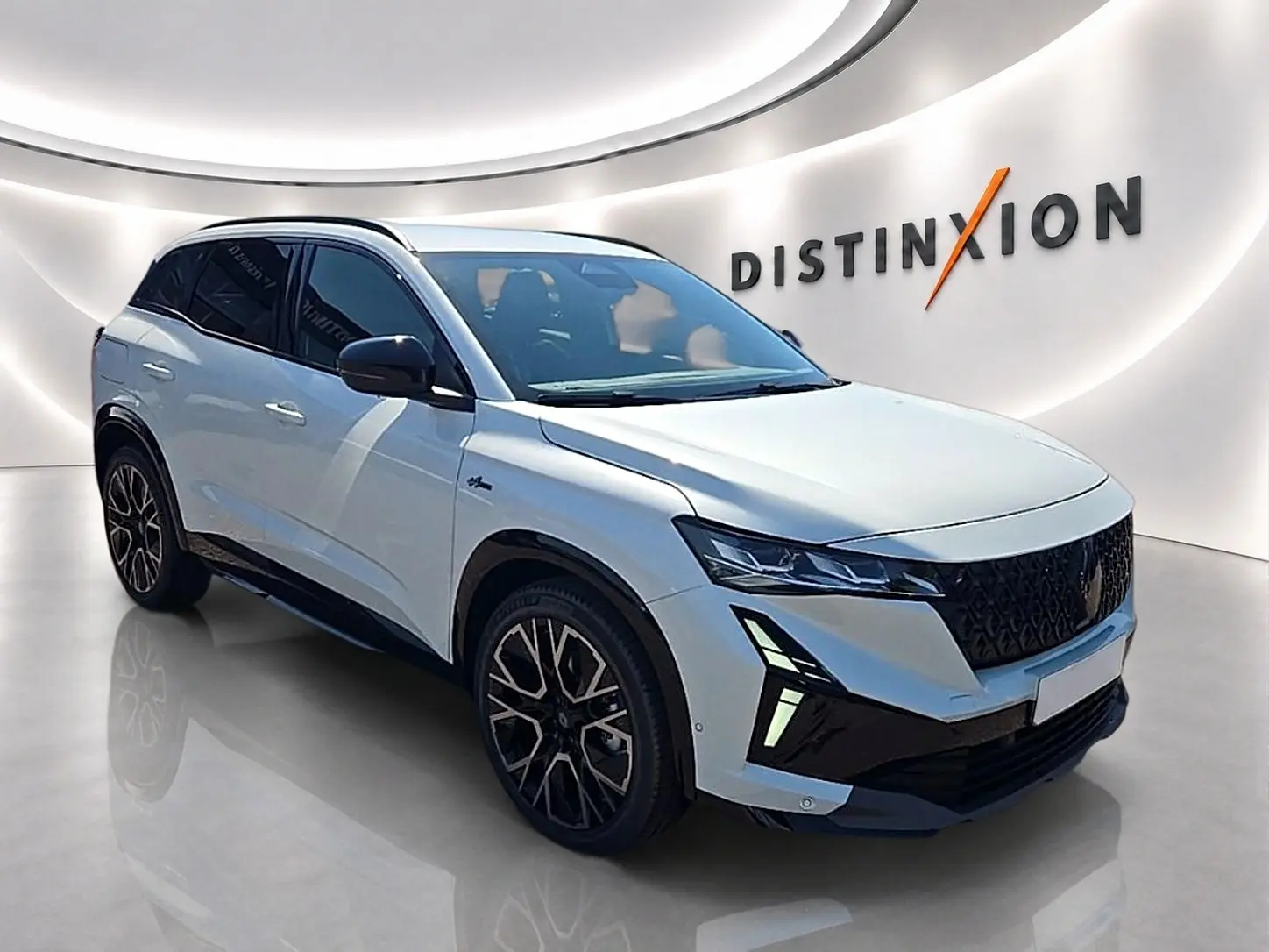 Renault Austral blanc nacré en 3/4 avant droit, avec jantes noires et phares LED distinctifs dans un showroom moderne.
