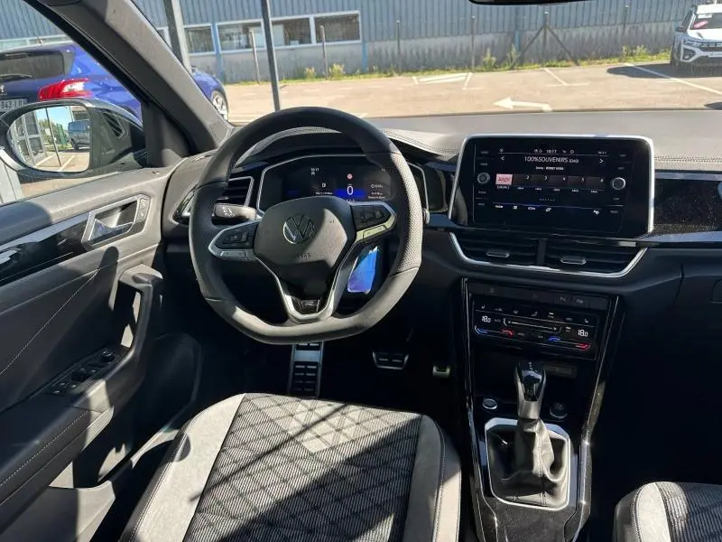 Vue intérieure du Volkswagen T-Roc 1.5 TSI R-Line 2025, tableau de bord et volant multifonction noir avec écran tactile central.