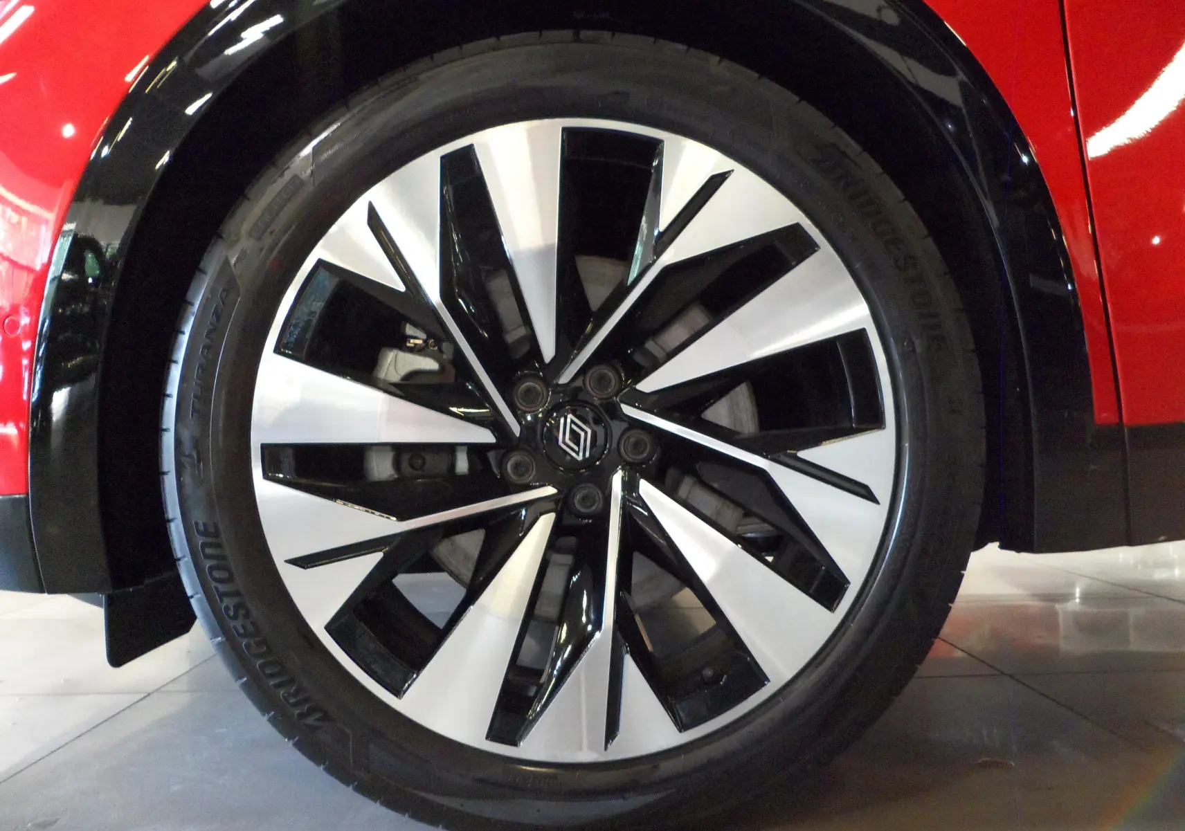 Gros plan sur la jante avant droite bicolore noire et argent du Renault Rafale E-Tech Rouge Flamme avec toit noir.