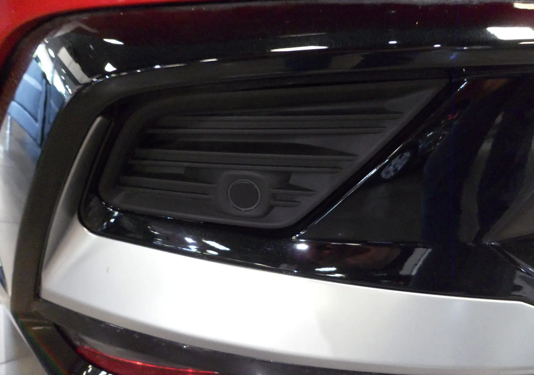 Gros plan sur la prise de recharge noire intégrée dans le côté arrière droit du Renault Rafale E-Tech Rouge Flamme.