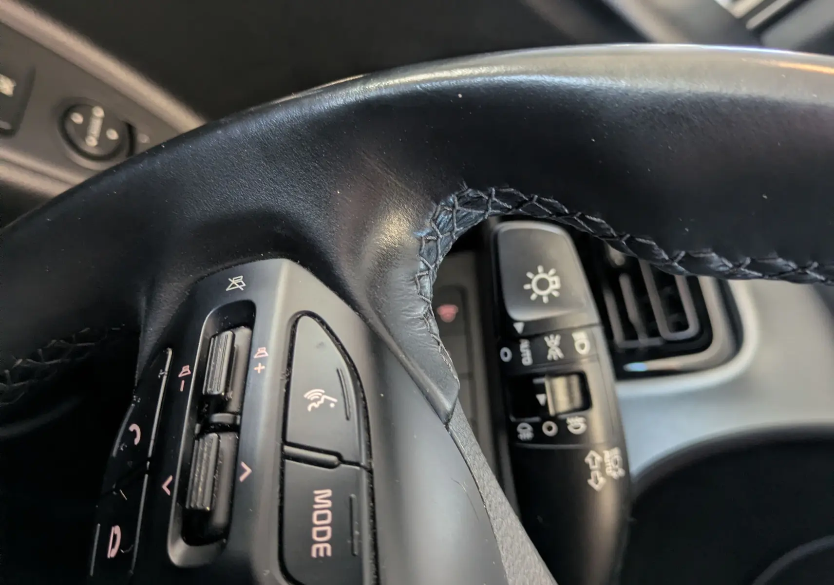 Gros plan sur les commandes au volant côté gauche du Kia Stonic 2022, intérieur noir avec détails fonctionnels visibles.