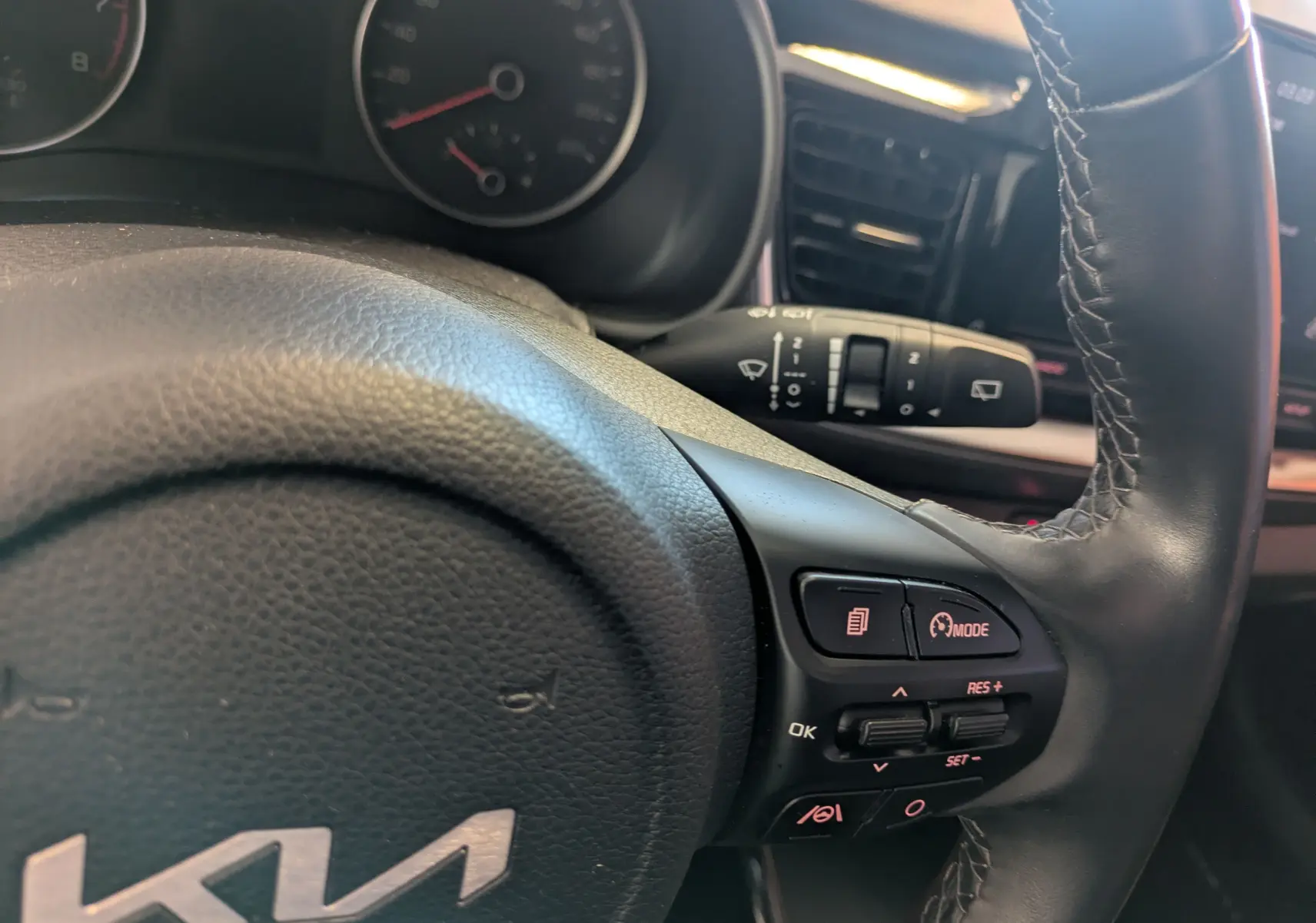 Gros plan sur le volant noir du Kia Stonic blanc, avec commandes intégrées et tableau de bord partiellement visible.