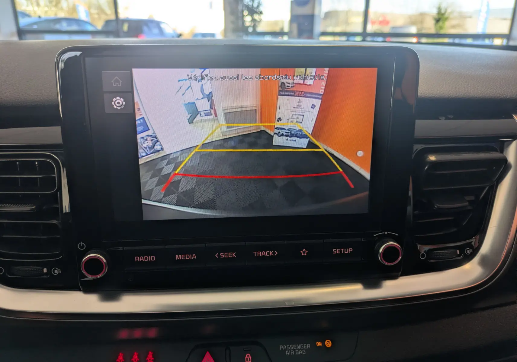 Vue de l'écran central du Kia Stonic blanc 2022 montrant la caméra de recul avec repères de stationnement colorés.