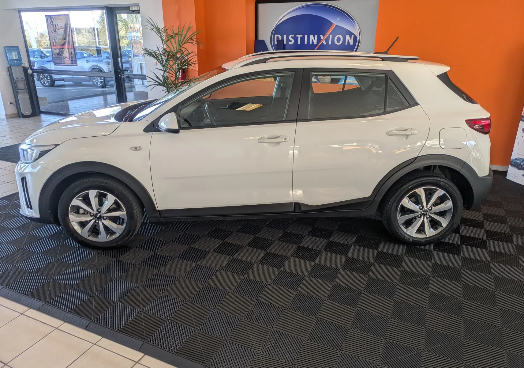 KIA Stonic blanc vue de profil côté gauche en intérieur, avec jantes alliage et toit noir contrasté.