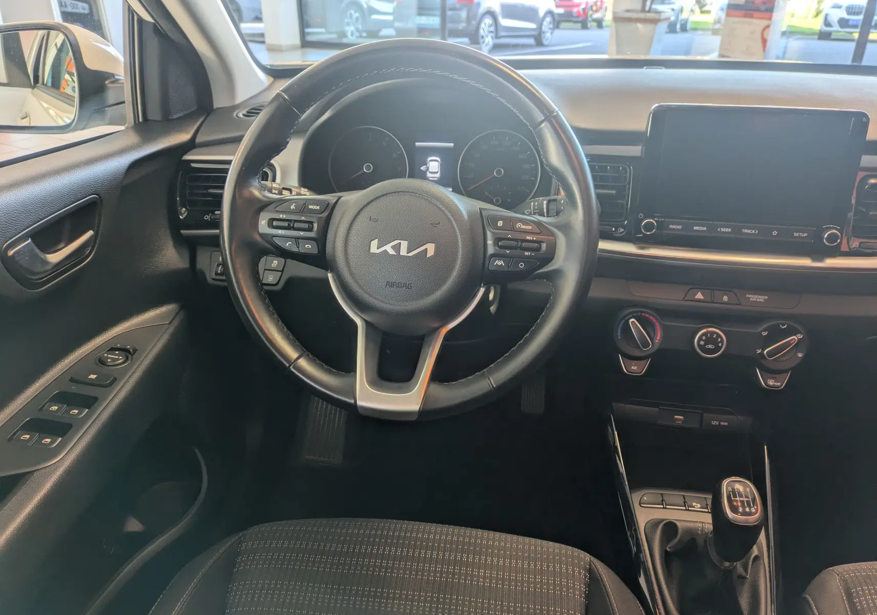 Vue intérieure centrée sur le volant noir et la console centrale du Kia Stonic 2022 avec boîte manuelle et écran tactile.