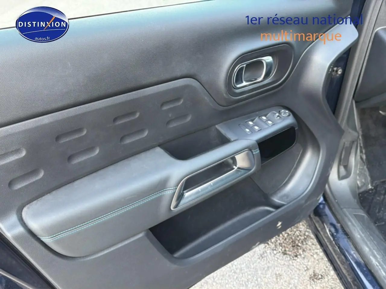 Vue rapprochée de la porte avant gauche du Citroën C5 Aircross bleu eclipse, montrant les commandes électriques et la poignée intérieure.