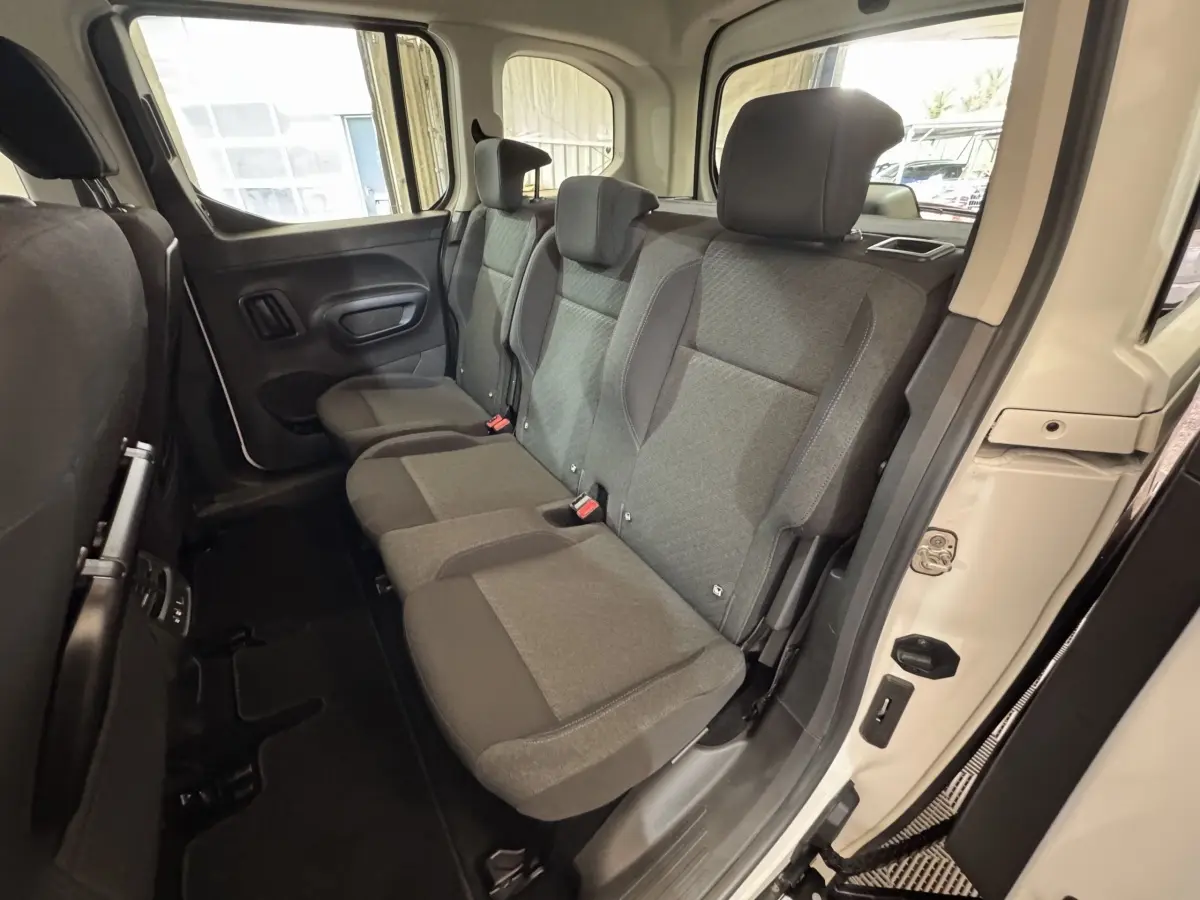 Vue intérieure côté droit sur la banquette arrière grise du Peugeot Rifter blanc, avec porte ouverte et habillage clair.