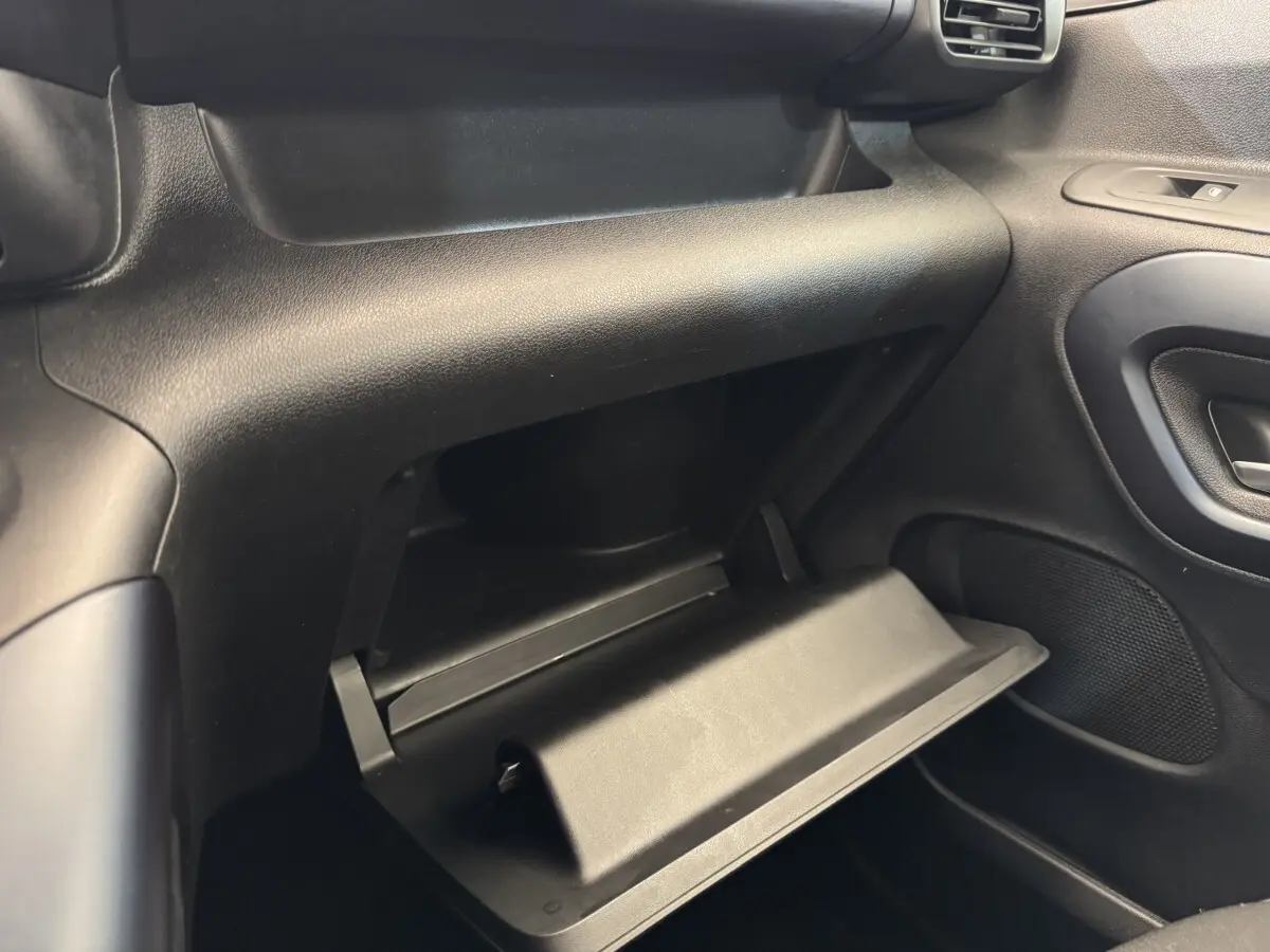 Vue intérieure côté passager du Peugeot Rifter 2019 BlueHDi 100 Allure, boîte à gants ouverte, tableau de bord noir.