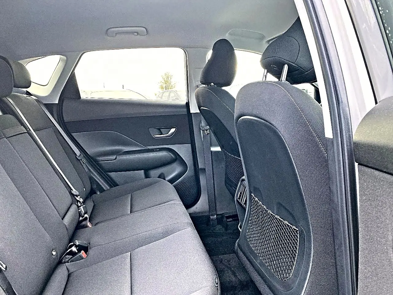 Vue intérieure côté droit montrant la banquette arrière grise et les dossiers des sièges avant du Hyundai Kona 2025.