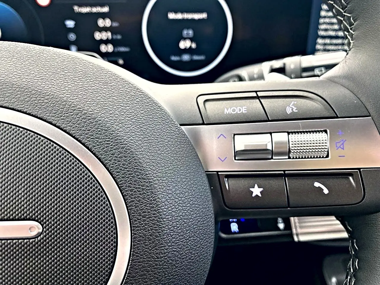 Gros plan sur le volant cuir multifonction gris du Hyundai Kona 2025 avec commandes audio et téléphone intégrées.