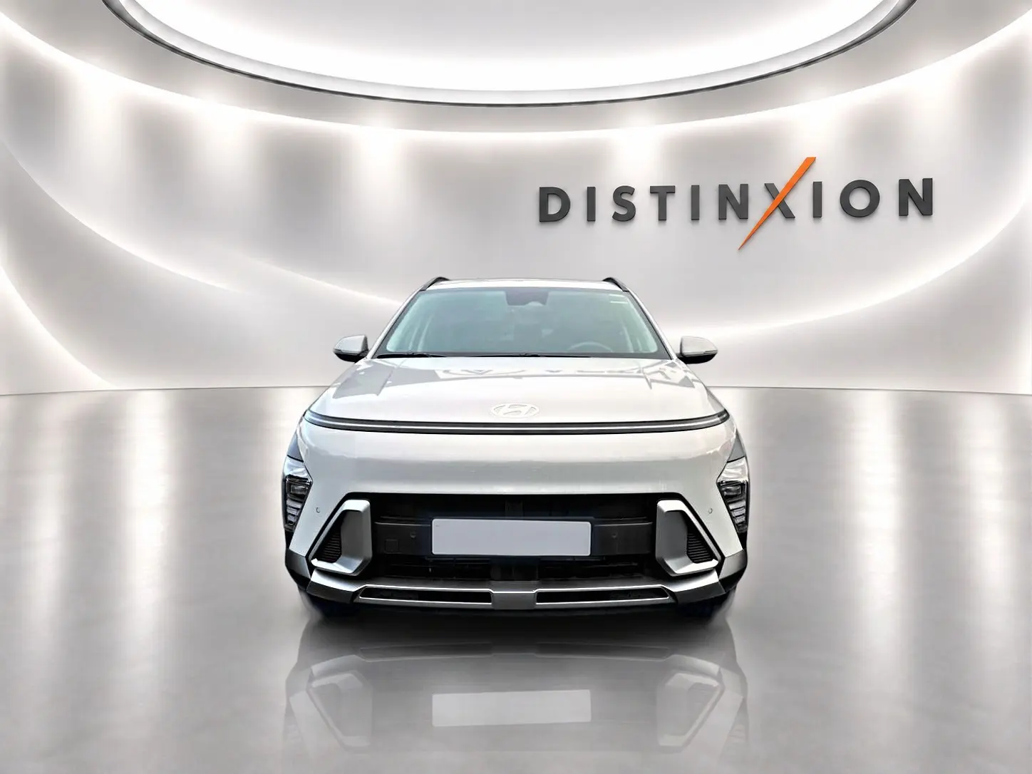 Vue avant d'un Hyundai Kona gris 2025 avec calandre noire et éclairage LED, sur fond blanc avec logo Distinxion.