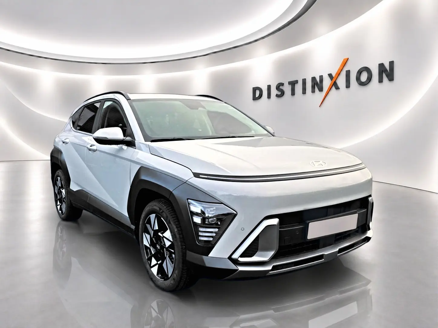 Hyundai Kona gris 2025 en 3/4 avant droit avec jantes alliage et protections noires contrastées.