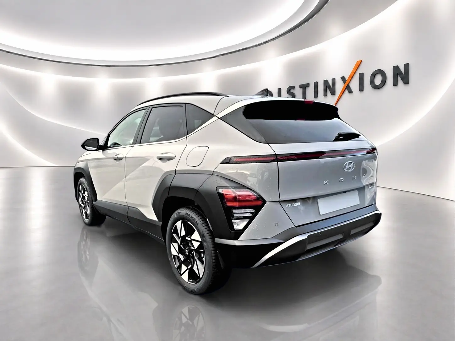 Vue 3/4 arrière droite d'un Hyundai Kona gris 2025 avec jantes alliage et feux arrière LED dans un showroom.