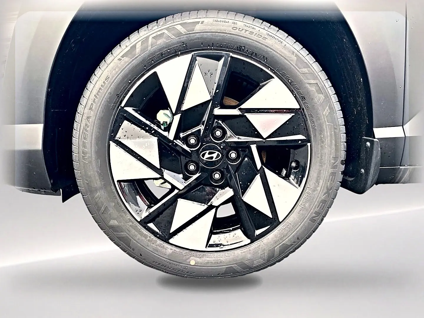 Gros plan sur la jante alliage noire et argentée du Hyundai Kona gris, mettant en valeur le logo Hyundai central.