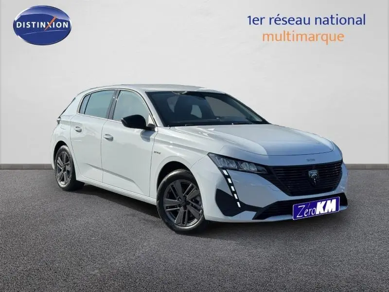 Peugeot 308 blanc Okénite vue 3/4 avant droit, avec calandre noire et feux LED verticaux distinctifs.