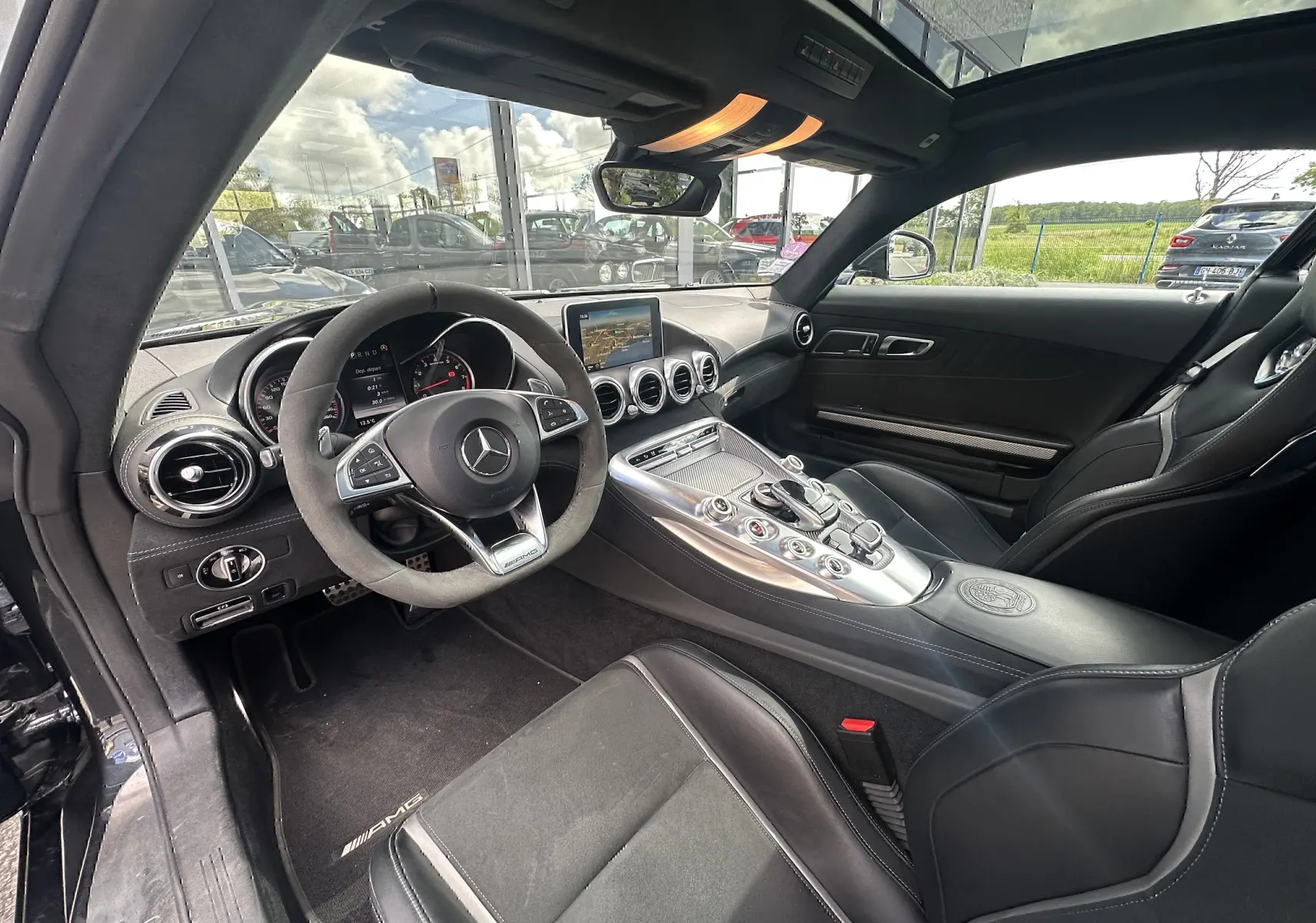 Intérieur noir du Mercedes AMG GT 2015 vu côté conducteur, avec volant sport et console centrale alu satinée.