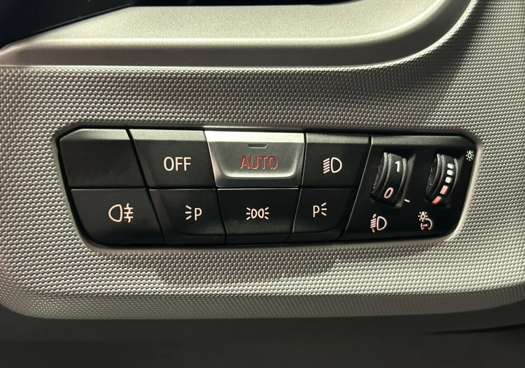 Panneau de commandes d'éclairage intérieur de la BMW Série 1 16d 2023, boutons noirs sur fond texturé gris.