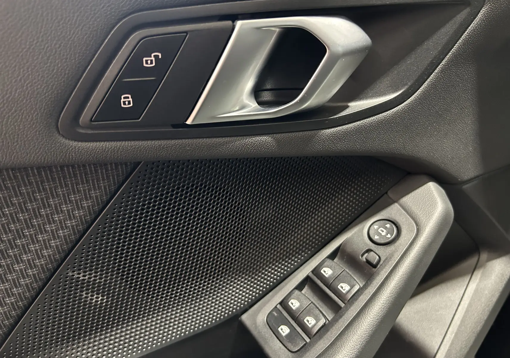 Poignée de porte intérieure côté gauche de BMW Série 1 16d 2023 noire avec commandes de verrouillage et vitres électriques.