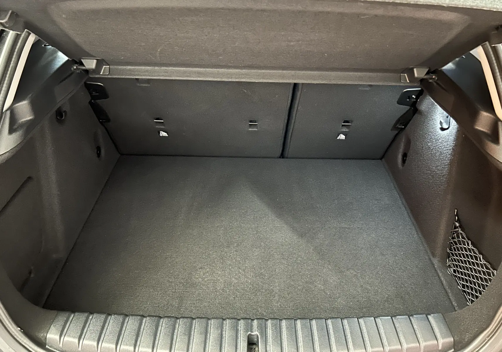 Coffre spacieux et propre de BMW Série 1 16d 116ch noir 2023, vue intérieure arrière avec filet de rangement latéral.