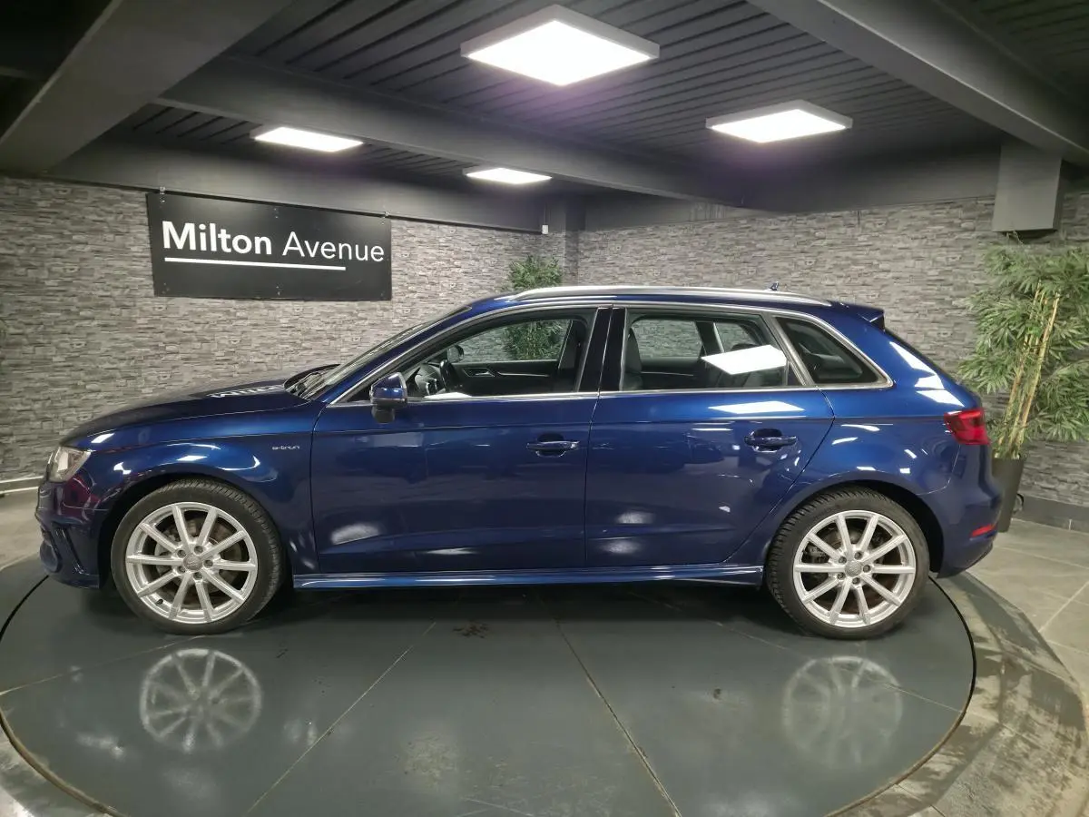 Audi A3 Sportback bleu vue de profil côté gauche dans un showroom avec jantes aluminium 10 branches.