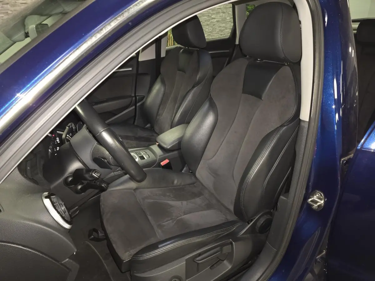 Intérieur avant droit d'une Audi A3 Sportback bleu, sièges sport en cuir et alcantara noirs, volant multifonction.