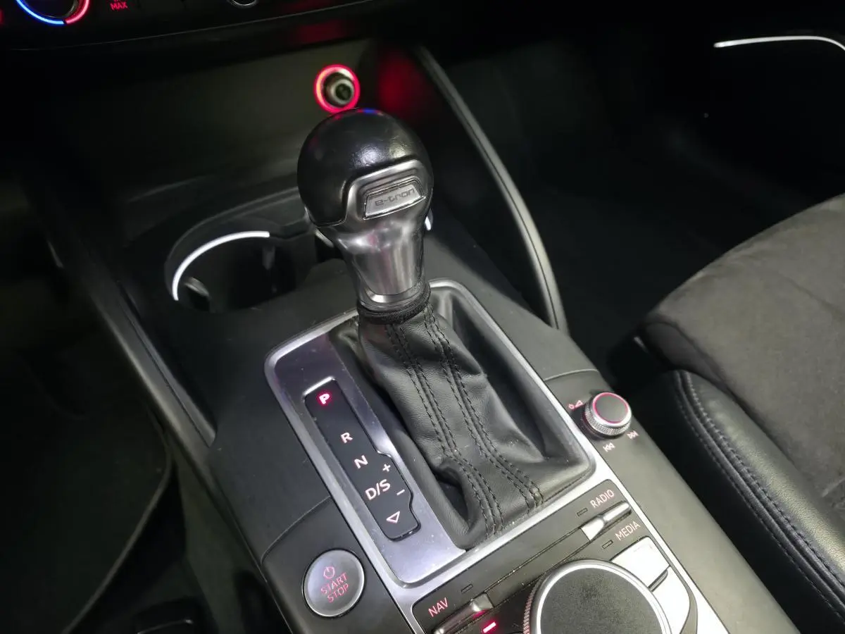 Gros plan sur la console centrale de l'Audi A3 Sportback hybride, levier de vitesse automatique e-tron et commandes MMI.
