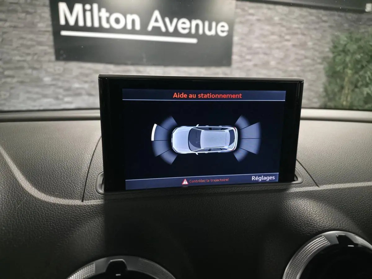 Écran MMI affichant l'aide au stationnement avec vue aérienne du break Audi A3 Sportback bleu en intérieur.