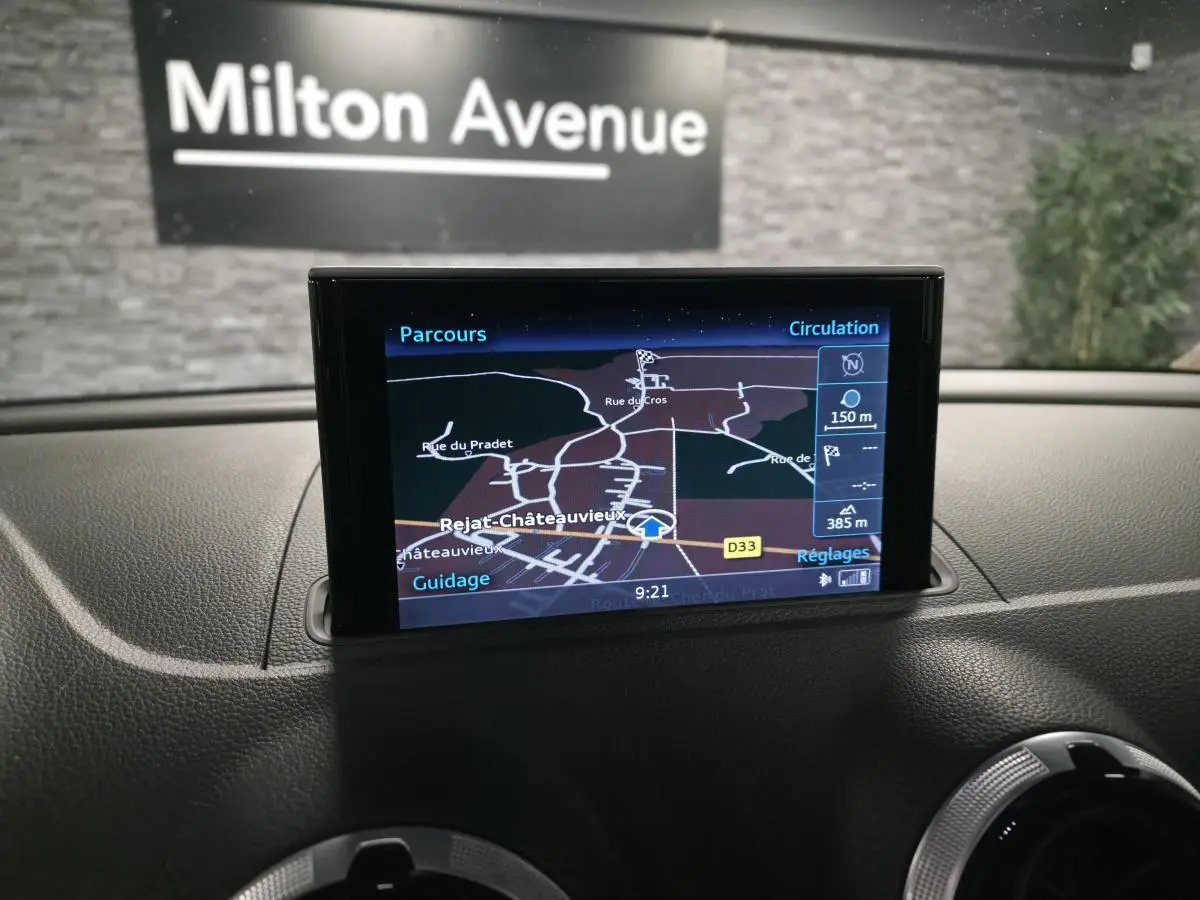 Écran MMI GPS Plus affichant la navigation dans l'habitacle d'une Audi A3 Sportback bleu, vue de face du tableau de bord.