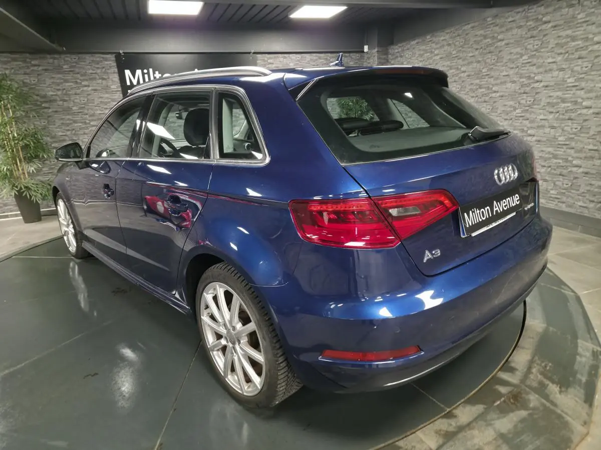 Audi A3 Sportback bleu en vue 3/4 arrière droit, avec jantes aluminium 10 branches et feux arrière LED.