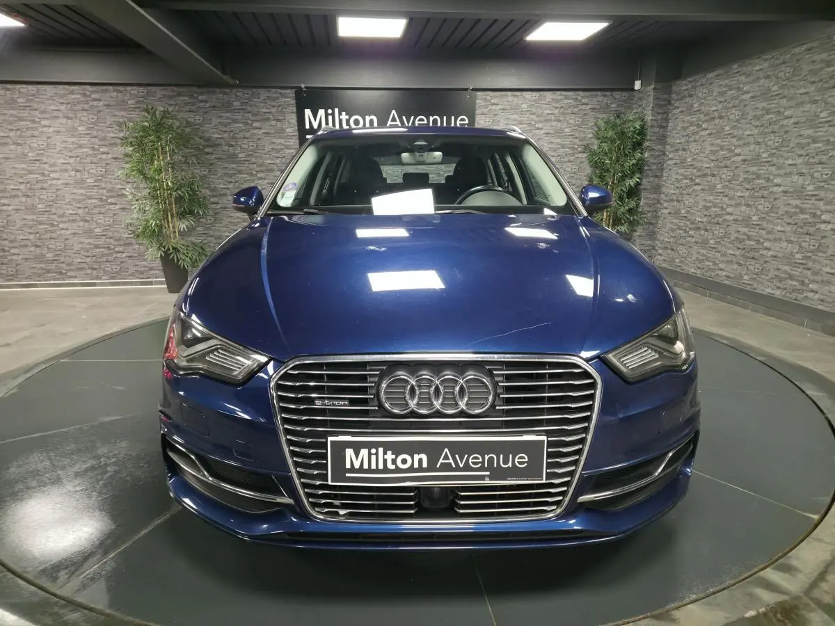 Vue frontale d'une Audi A3 Sportback bleu métallisé avec calandre chromée et logo e-tron visible.