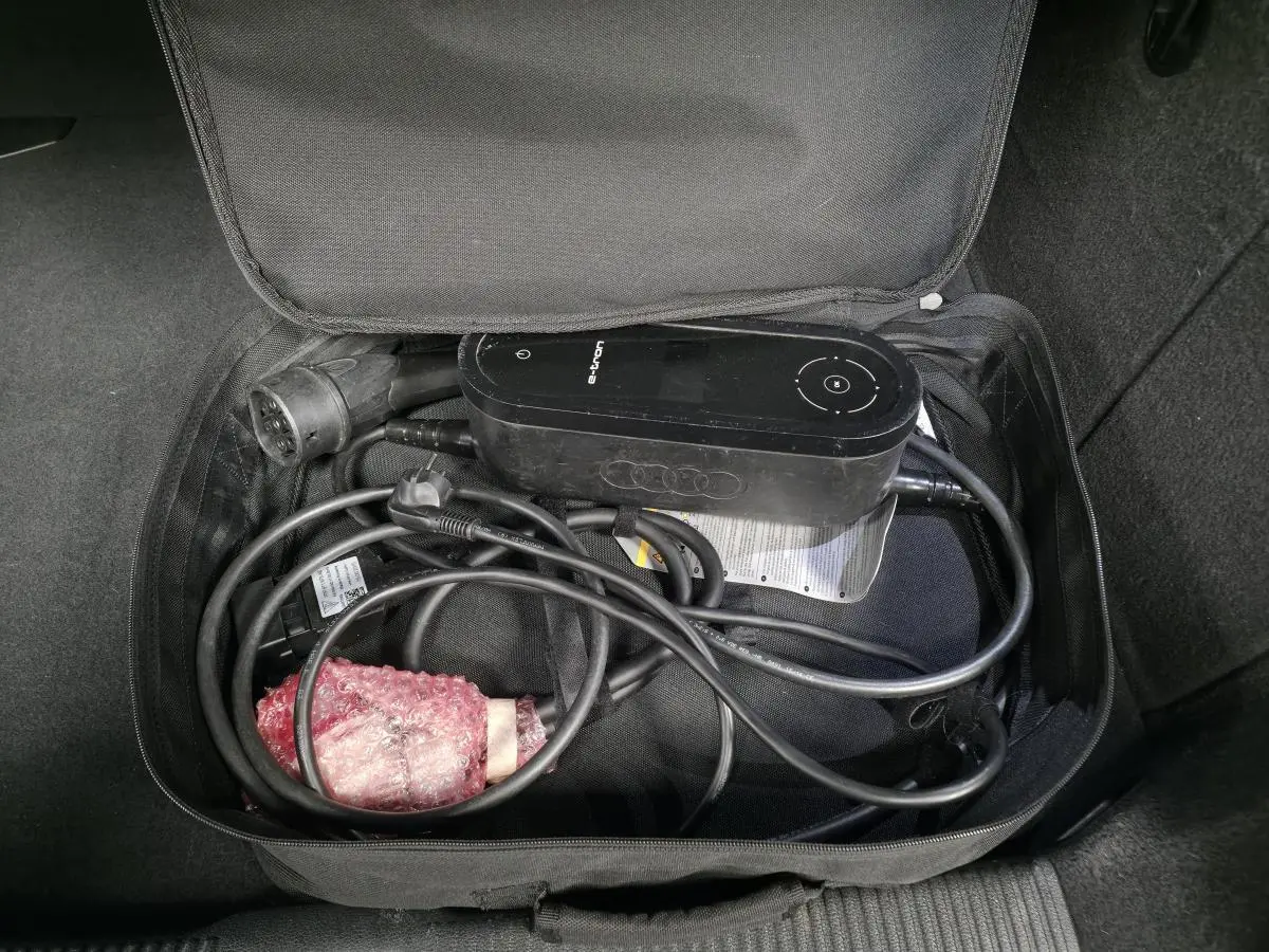 Gros plan sur le câble de recharge e-tron noir rangé dans un sac dans le coffre d'une Audi A3 Sportback bleu.